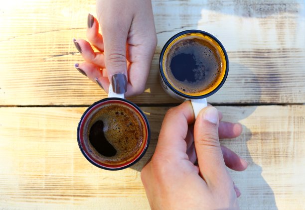 一男一女手拿咖啡杯对面。图片下载