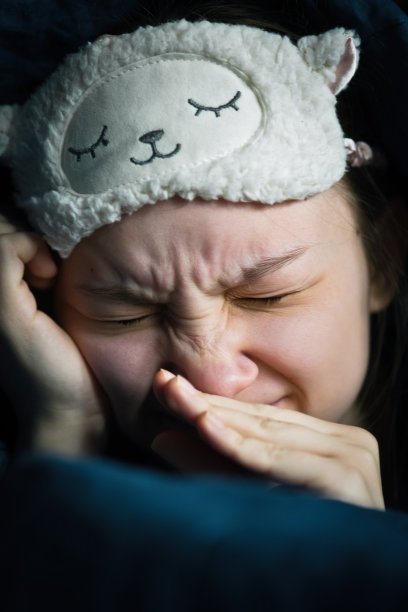 健康睡眠、懒惰和心理健康概念:小女孩睡意朦胧裹在毯子里图片下载