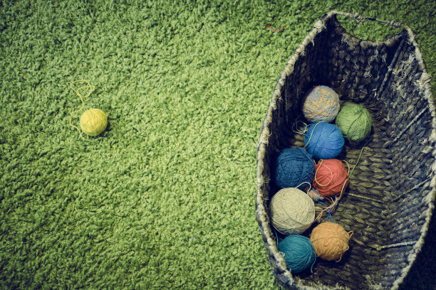 Сolor满球的毛线针在柳条篮子在一个绿色的背景图片下载