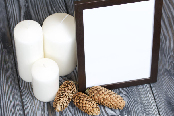 木制的相框，白色的领域为题字或图片。附近是杉木蜡烛。图片下载