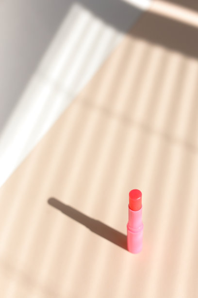 粉色卫生口红在条纹阴影背景图片下载