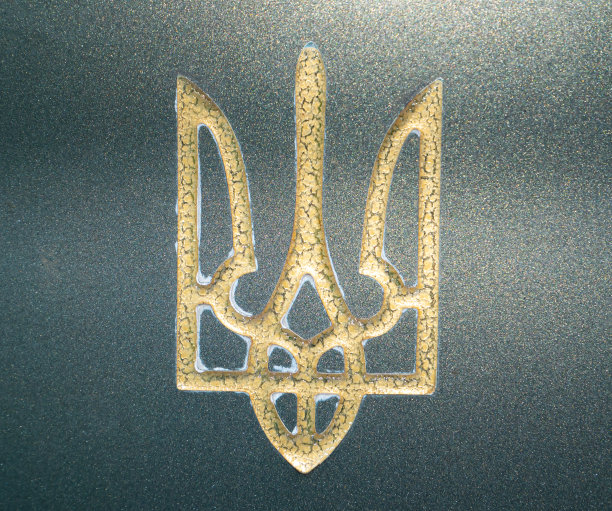 金色的乌克兰三叉戟纹章在绿色大理石上。图片下载