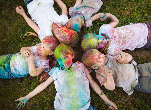 孩子们躺在草地上。孩子们涂上胡里节的颜色躺在草地上图片下载