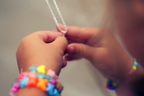 孩子们的手拿着一个漂亮的链子，有一个垂饰那么近图片下载