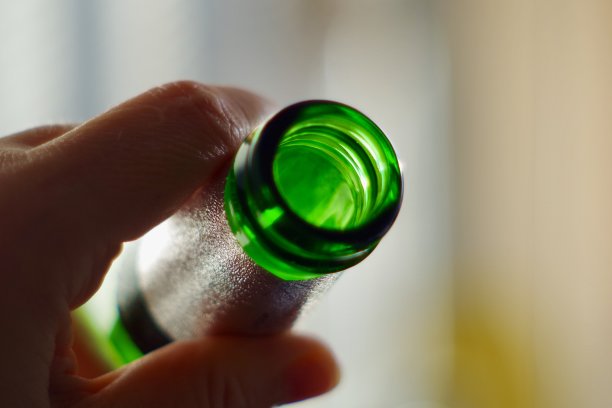 手握无品牌的绿色啤酒瓶的特写图片下载