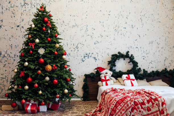 卧室的内部用一个绿色的圣诞树床和红色的礼物为新年装饰冬季假期图片下载