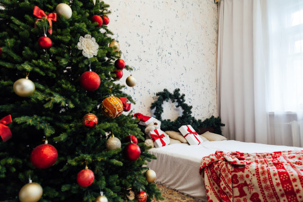 卧室的内部用一个绿色的圣诞树床和红色的礼物为新年装饰冬季假期图片下载