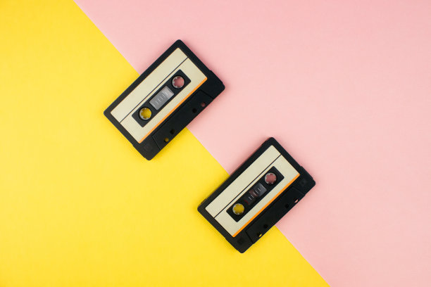 复古的磁带平躺在彩色的黄色和粉红色的背景顶部视图与拷贝空间。极简80年代风格的创意设计。音乐、广播、dj概念。网络旗帜模板。股票的照片。图片下载