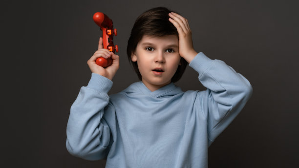 不幸的男孩站着，手里拿着操纵杆，手放在头上。哦，不，我没有赢。童年的概念图片下载