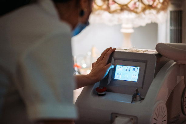 亚洲华人女性美容师在美容院准备和预热激光机图片下载