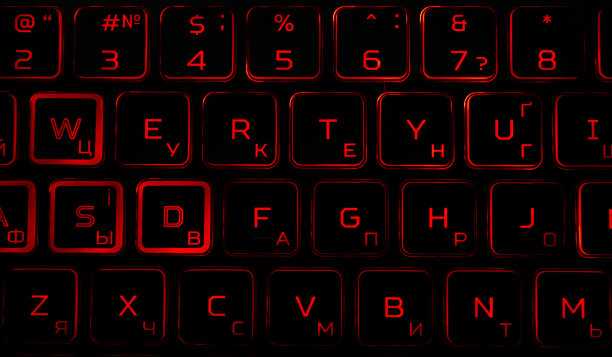 黑色的电脑键盘和红色的背光在黑暗中。图片下载