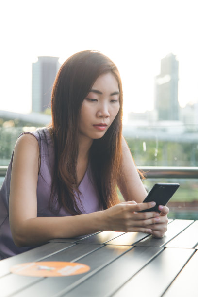 女性自由职业者用手机工作，独自坐在城市里图片下载