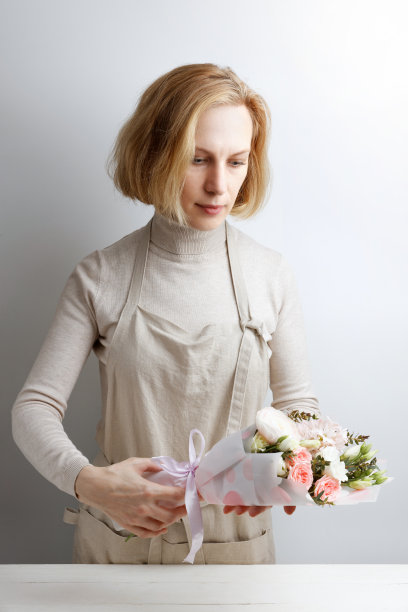 花店女采摘花束的肖像在白色木制桌子上图片下载