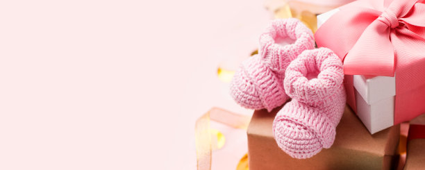 美丽的组成与粉红色的婴儿靴和礼物盒在粉红色的背景。婴儿送礼会，一周岁节日贺卡，拷贝空间，横幅的概念图片下载