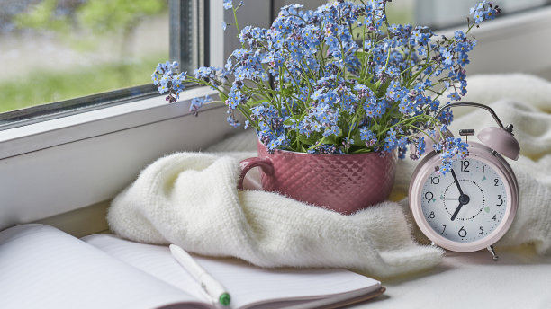 白色温暖的格子毯子和笔记本，眼镜放在木制的乡村长椅上。照片色调，选择性聚焦。温馨的家居静物:窗台上盛开着温暖格子图案的春花图片下载