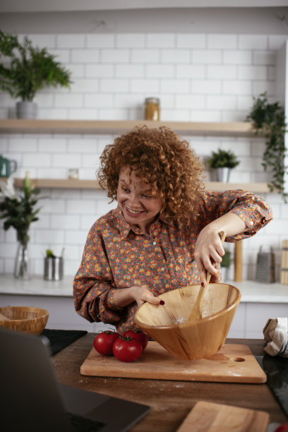 年轻女子一边做饭一边读菜谱。图片下载