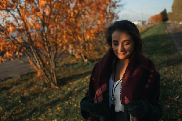 户外时尚照片年轻美丽的女士在红色围巾和深灰色外套包围秋天的树叶图片下载