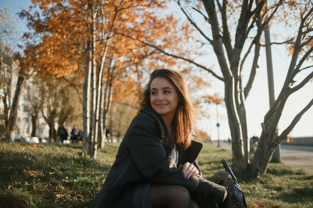 户外时尚照片年轻美丽的女士在红色围巾和深灰色外套包围秋天的树叶图片下载