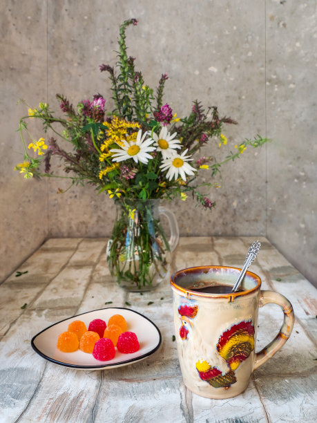 简单的午餐，茶水放在一个大陶瓷杯里，上面有一只公鸡的照片，还有一个放着橘子酱的碟子，一束放在玻璃杯里的野花图片下载