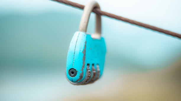 蓝色的旧锁挂在电缆与模糊的自然背景。安全生活新常态理念。图片下载