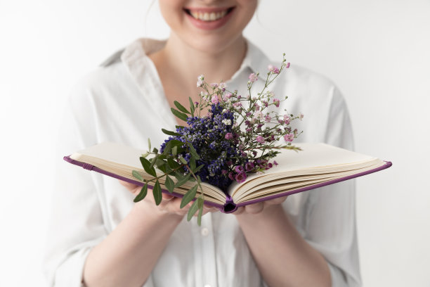 快乐的年轻女子拿着打开的书和鲜花图片下载
