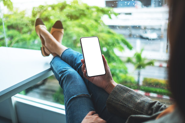 一位女士坐在办公室里，手里拿着手机，手机的桌面屏幕是空白的图片下载