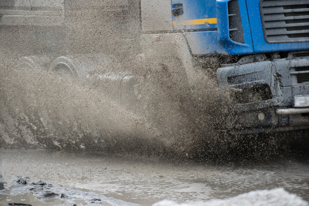 汽车运动通过大水坑从车轮溅在街道道路上。水溅雨纹理图片下载