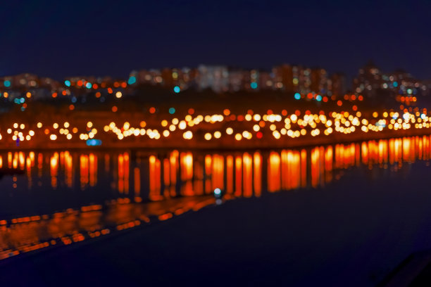 抽象模糊的散景的城市，霓虹夜光，灯火通明，各种色彩在夜晚映在湖面上。城市生活在傍晚，城市背景散焦图片下载