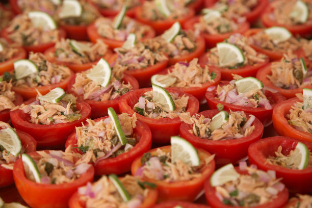 自助餐开胃菜:西红柿塞满金枪鱼罐头和洋葱，配上一片柠檬。高质量的照片图片下载