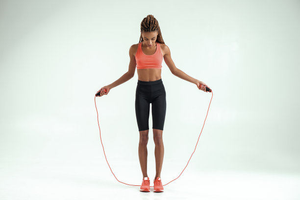 完美的身体。全长美丽的非洲妇女在运动服跳绳，而在演播室的灰色背景下锻炼图片下载