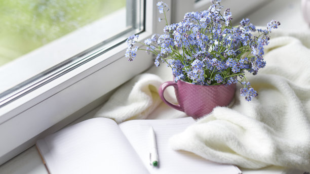 白色温暖的格子毯子和笔记本，眼镜放在木制的乡村长椅上。照片色调，选择性聚焦。温馨的家居静物:窗台上盛开着温暖格子图案的春花图片下载