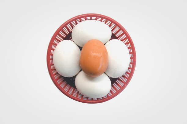 四个咸蛋和一个鸡蛋在红色的篮子在白色的背景图片下载