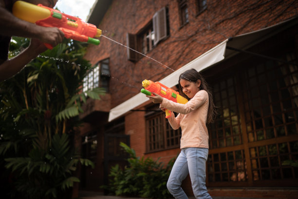 父亲和女儿在后院玩水枪图片下载