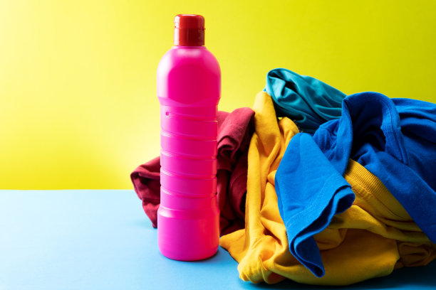 塑料瓶的清洁用品堆放在桌子的背景彩色衣服。图片下载