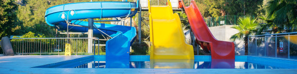 五颜六色的孩子们在户外游泳池附近的水上乐园滑梯图片下载
