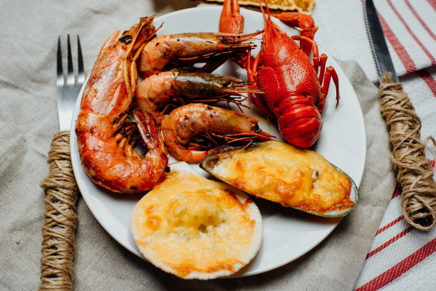 白盘子里有水煮小龙虾，烤扇贝和贻贝，炸海螯虾和小虾图片下载