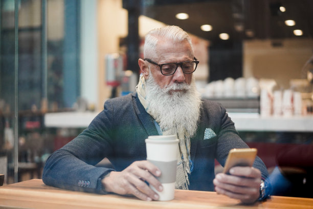 高级商务人士使用智能手机应用程序，而喝咖啡在咖啡馆酒吧-时髦的企业家做早餐-工作，上午休息和技术概念-窗户从外部的观点-关注脸图片下载