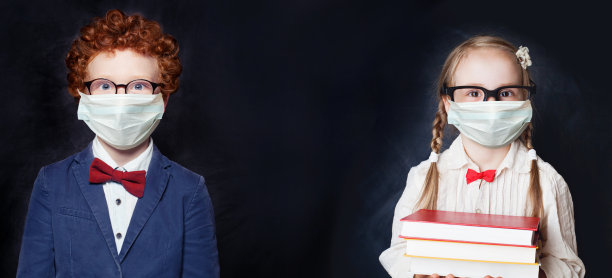 可爱的孩子们戴着防护口罩，打着黑色横幅背景，回到学校和covid-19概念图片下载