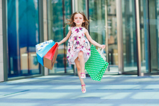 可爱的小女孩在购物。一个拿着购物袋的孩子的肖像。购物。女孩图片下载