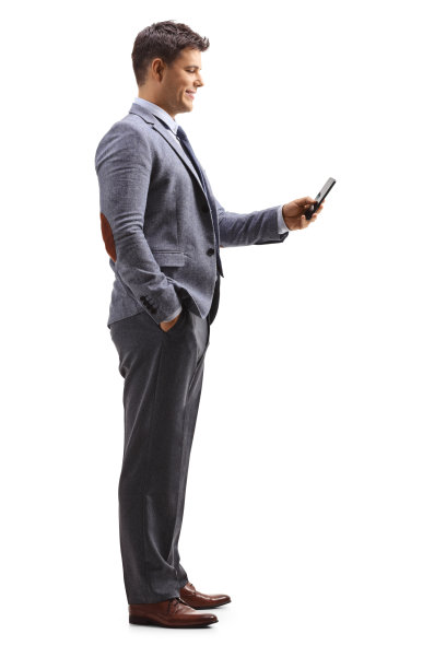一个站着拿着手机的职业年轻人的全长侧面照片图片下载