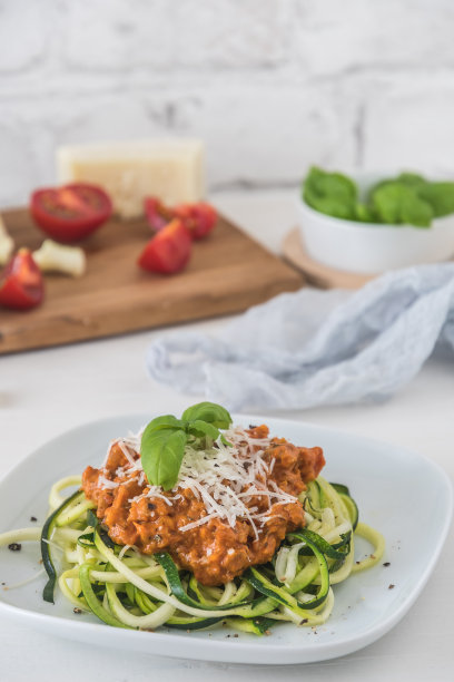 肉酱西葫芦面:西葫芦面加肉或素酱油和帕尔马干酪。低碳水化合物，生酮，古营养。垂直库存照片与复制空间。图片下载