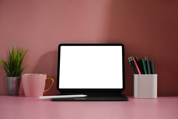 一个白色空白屏幕的平板电脑放在一个妇女的桌子上，周围摆满了各种设备。图片下载