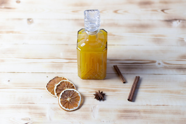 橘子酒在水晶瓶与香料在木制背景图片下载