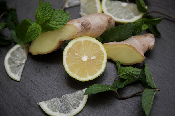 切片的柠檬和生姜根与薄荷枝在黑暗的背景。高质量的照片图片下载