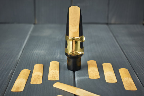 更换簧片和萨克斯管吹口与夹和金色调整螺丝在灰色木桌上图片下载