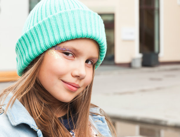 小女孩戴着明亮的绿色帽子和闪闪发光的化妆品，特写图片下载