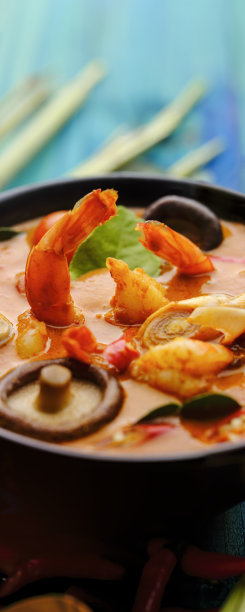 在国际上享有盛名的香辣泰式椰子汤“冬阴功”，在绿松石色的木板桌子背景上与整个柠檬草一起放在一个碗里。图片下载