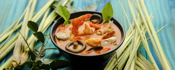 在国际上享有盛名的香辣泰式椰子汤“冬阴功”，与整个柠檬草和青柠叶一起放在绿松石色的木板桌上。图片下载