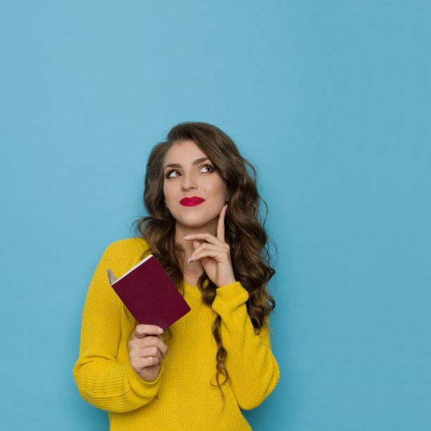 黄色毛衣微笑的女人拿着护照，抬起头，梦想着图片下载