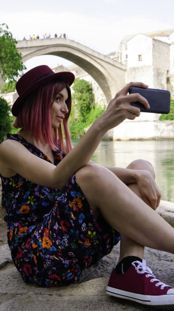 波斯尼亚和黑塞哥维那，一名白人妇女在莫斯塔尔老桥下自拍。图片下载